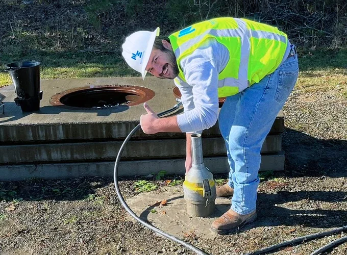 Concrete field technician performing fresh concrete testing with ACI field testing equipment at a construction site.