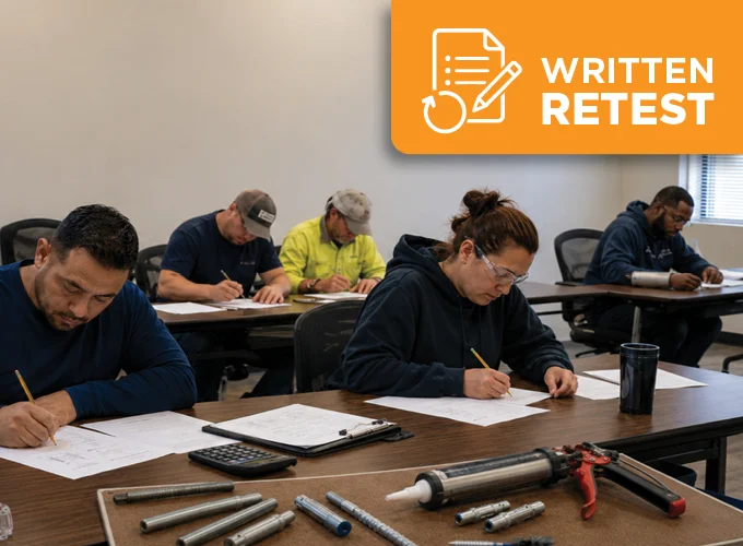 Multi-racial group of construction professionals taking an adhesive anchor written retest in a classroom with anchor installation tools on the table.